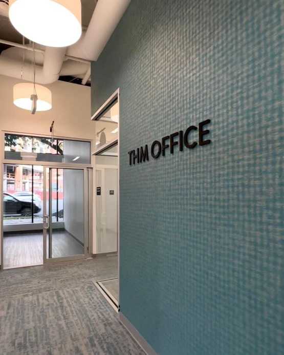 The contemporary lobby and entrance area of **THM Offices**, featuring a textured blue accent wall and modern glass doors.